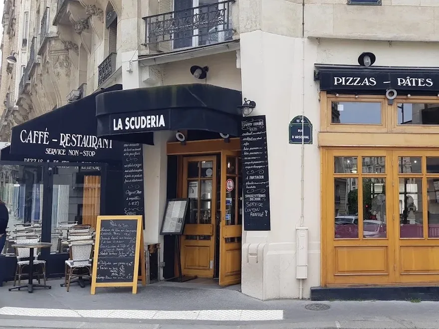 La façade noire de La Scuderia Caffè à l'angle de la rue — store « Caffè-Restaurant », ardoise du jour et terrasse
